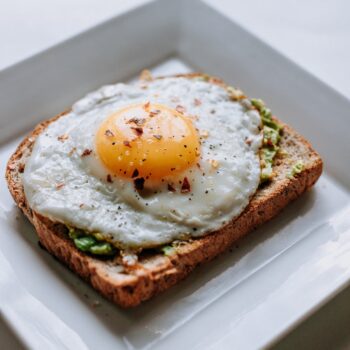 A fried egg with avocado on top of sprouted grain toast.