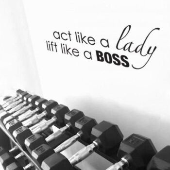 Racks of various sized free-weights with an inspirational quote on the wall that says, "Act Like a Lady, Lift Like a Boss."