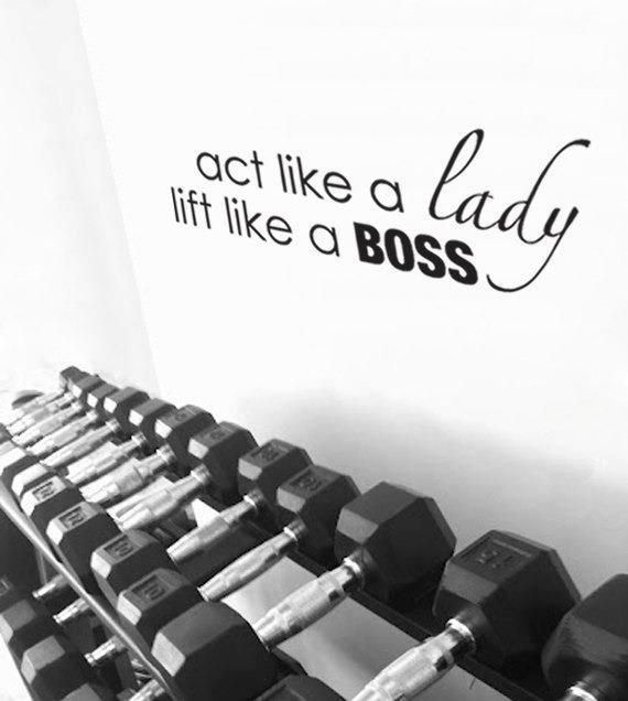 Racks of various sized free-weights with an inspirational quote on the wall that says, "Act Like a Lady, Lift Like a Boss."