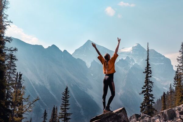 woman hiking in the mountains and reaching for the sky with happiness