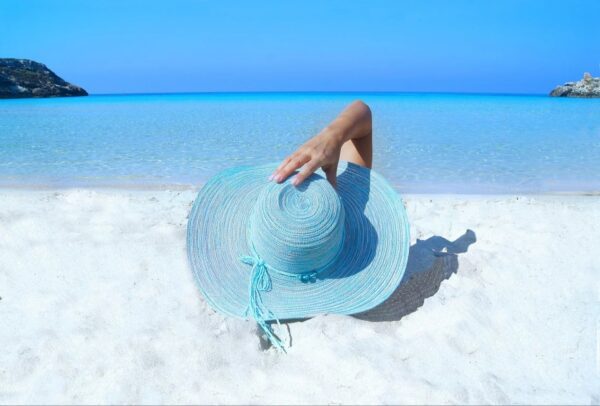 Woman relaxing on beach enjoying summer self-care.